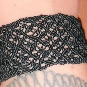 Bracelet en micromacramé noir porté au poignet, motif diamant ajouré artisanal