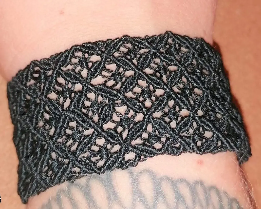 Bracelet en micromacramé noir porté au poignet, motif diamant ajouré artisanal